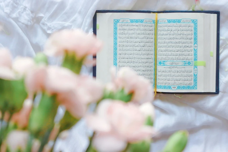 an open book sitting next to flowers on a table