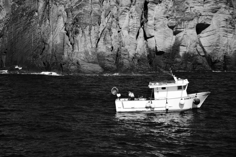 a boat in the water next to some cliffs