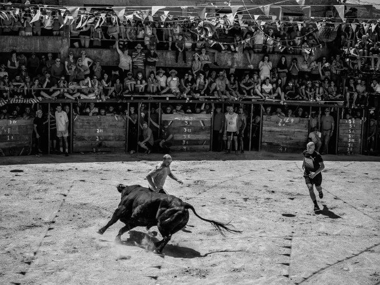 a group of people watch as a man rides a bull