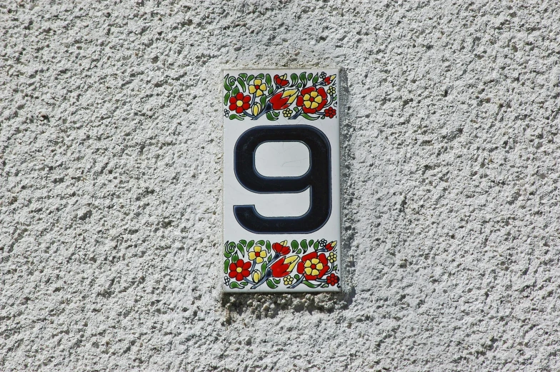 the number nine is decorated with flower on a stone wall