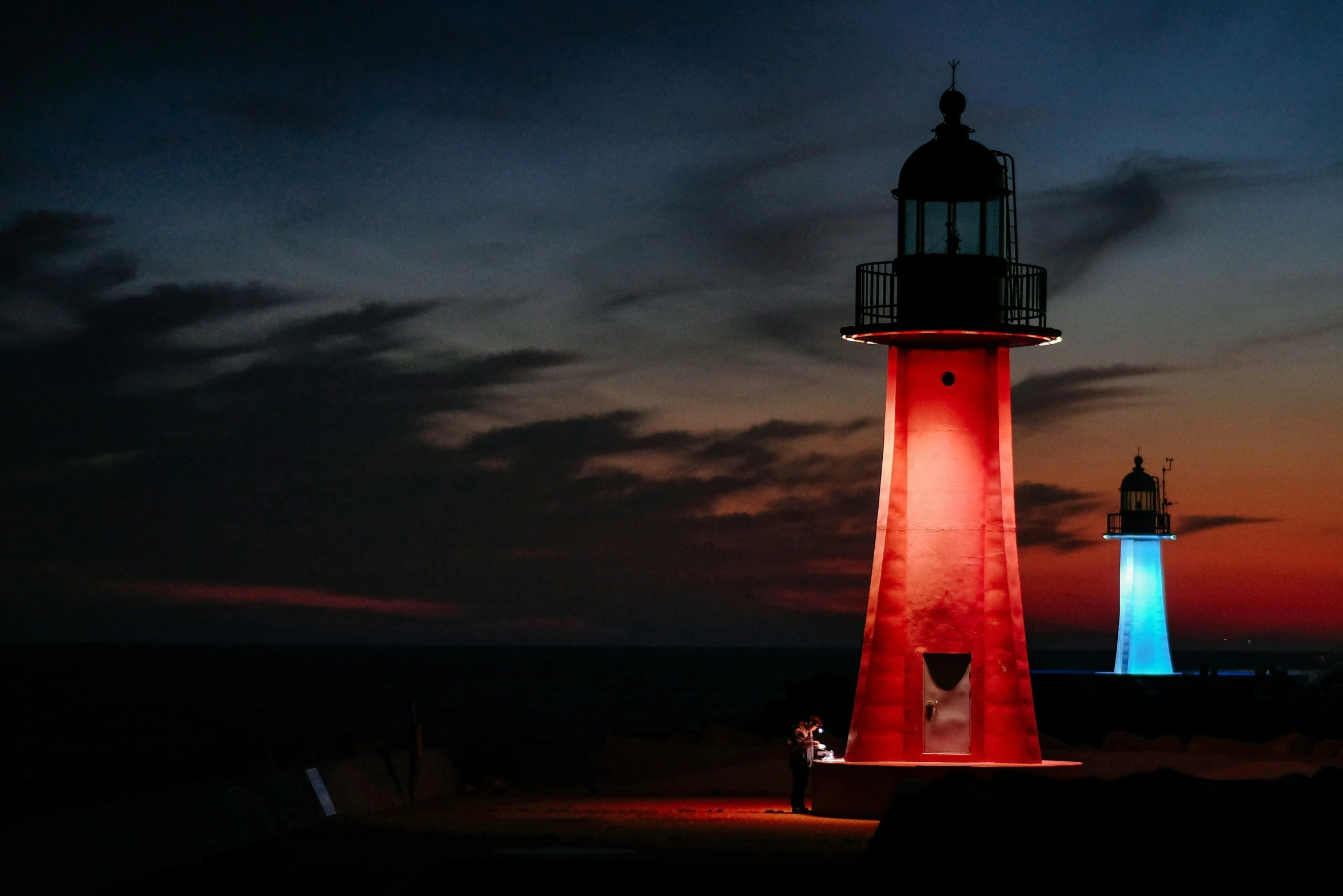 a red and white light tower sitting at the end of a pier