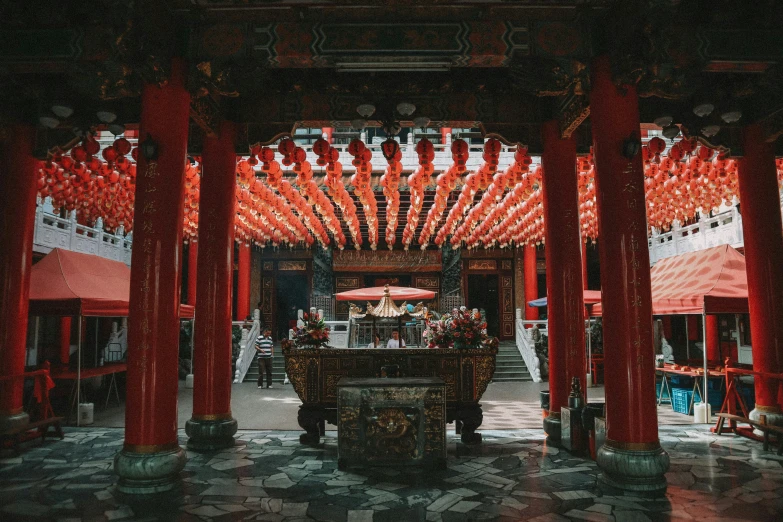 an archway and table beneath many tall red umbrellas