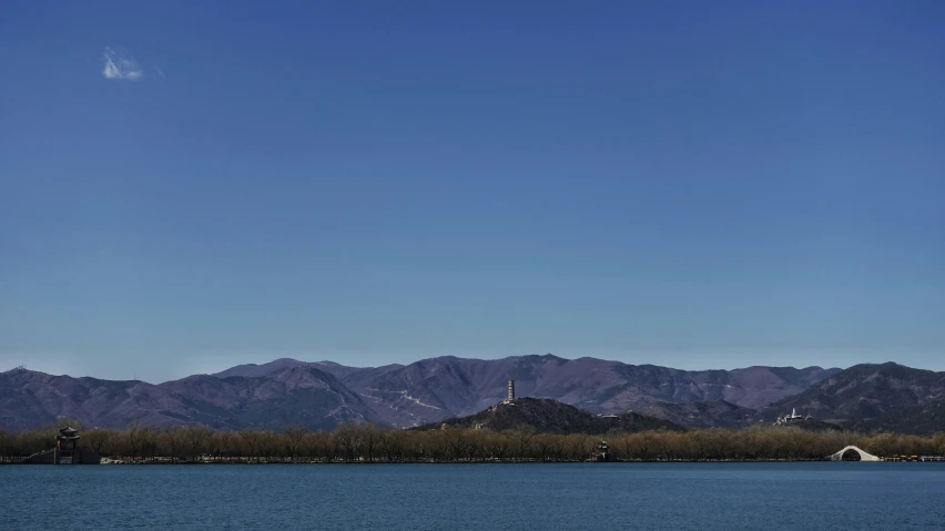 a blue body of water sitting below a group of mountains