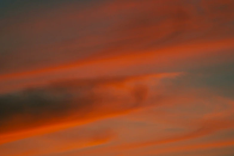 an airplane is flying in a colorful sky at sunset