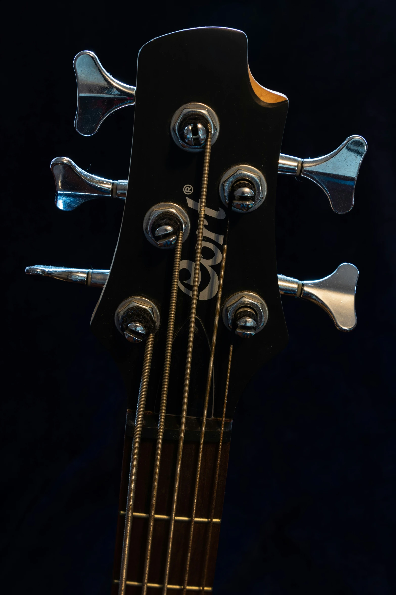 an old black guitar with strings and some black background