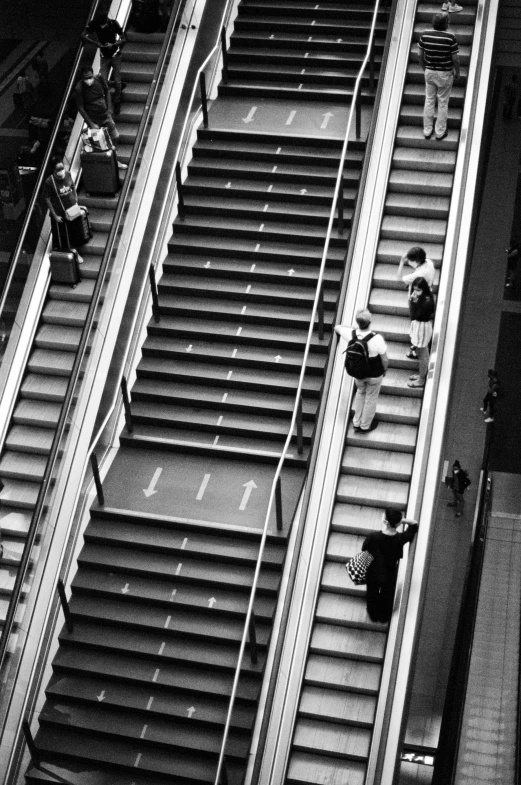 an overhead s of people walking down a stairway on an escalator