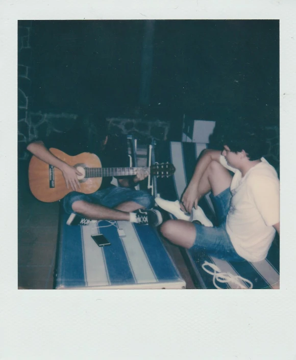 two men sitting next to each other playing guitars