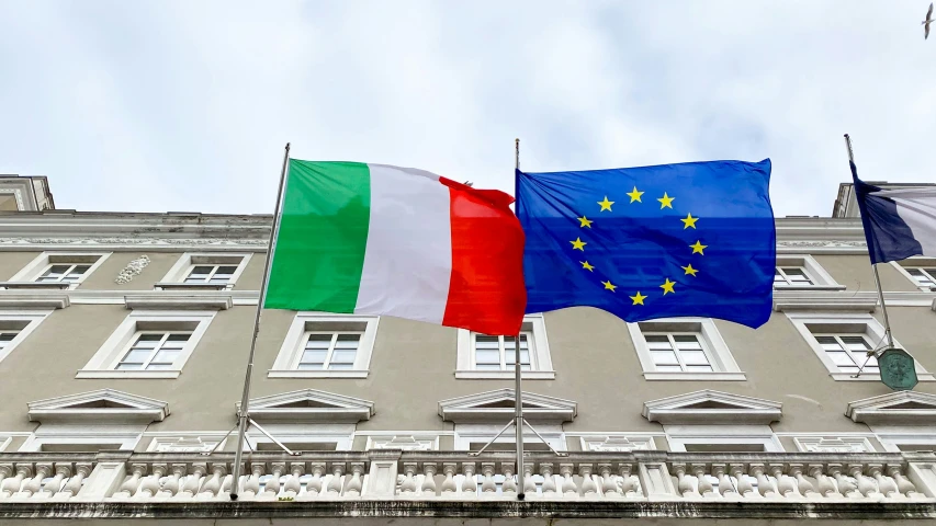 two flags are waving in front of the building