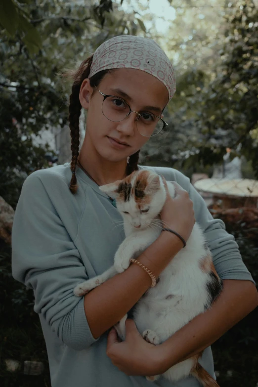 a girl in glasses holding a cat and looking at the camera