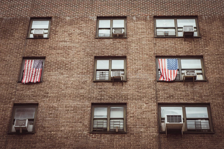 three american flags reflected in several windows of a brick building