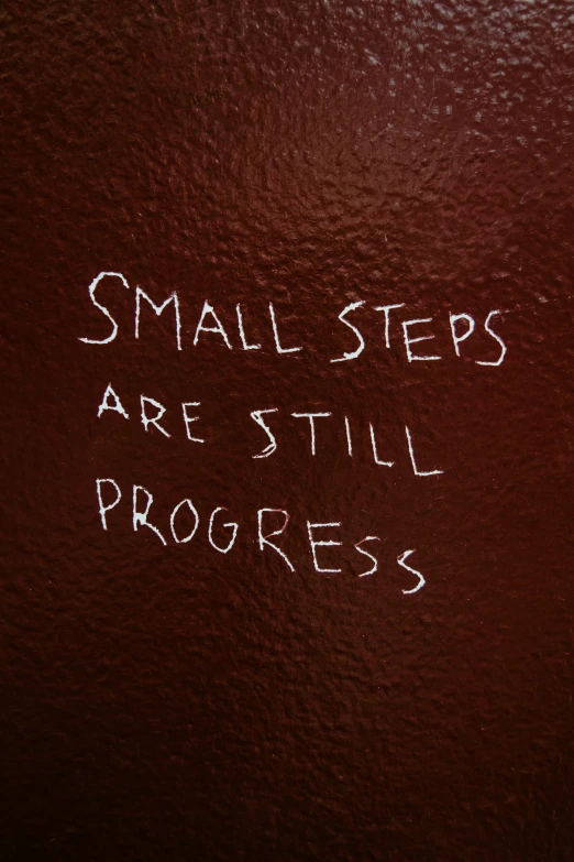 small steps are still progress written on a piece of dark colored wood