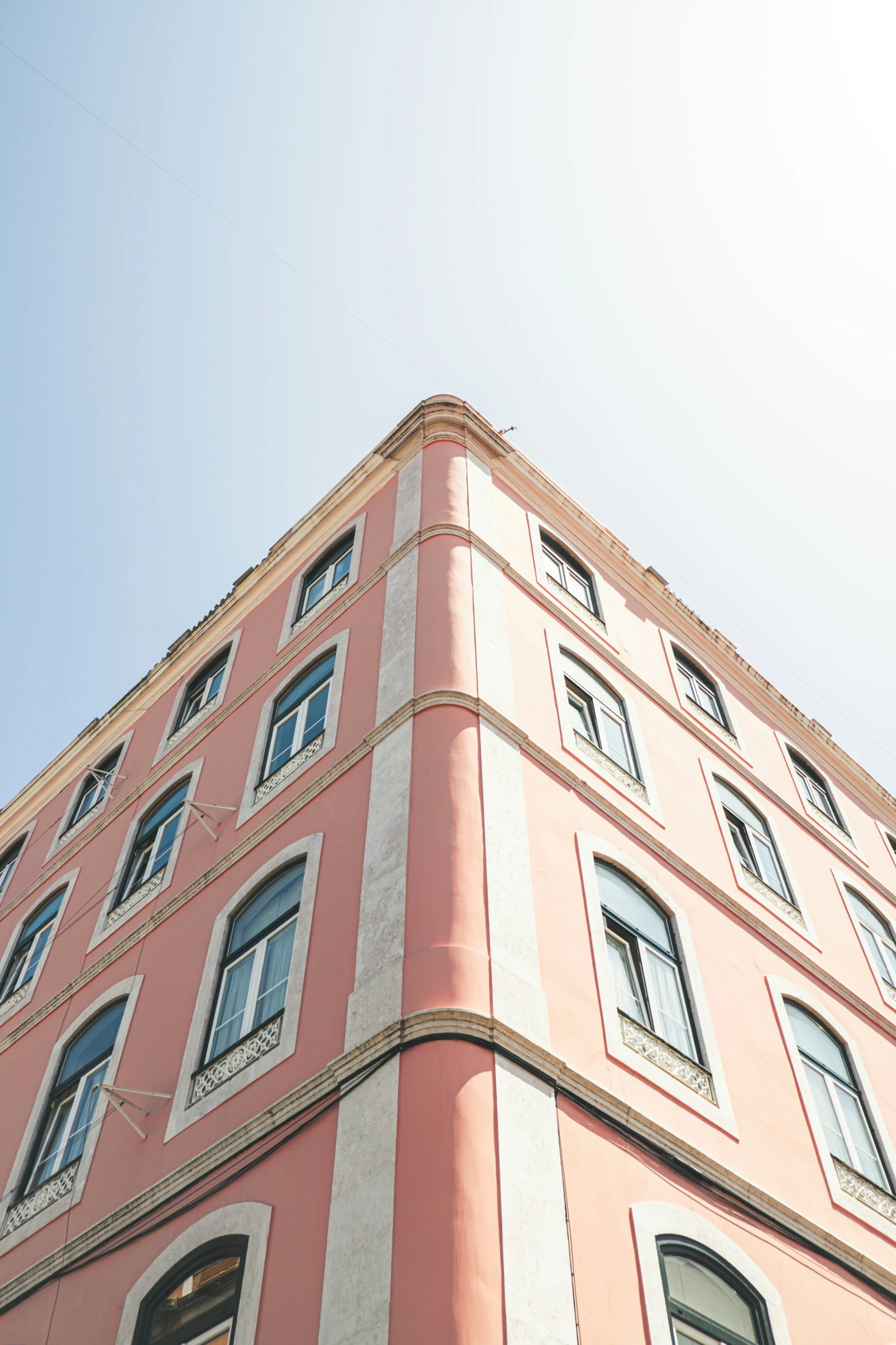 a pink building is standing tall against a bright blue sky