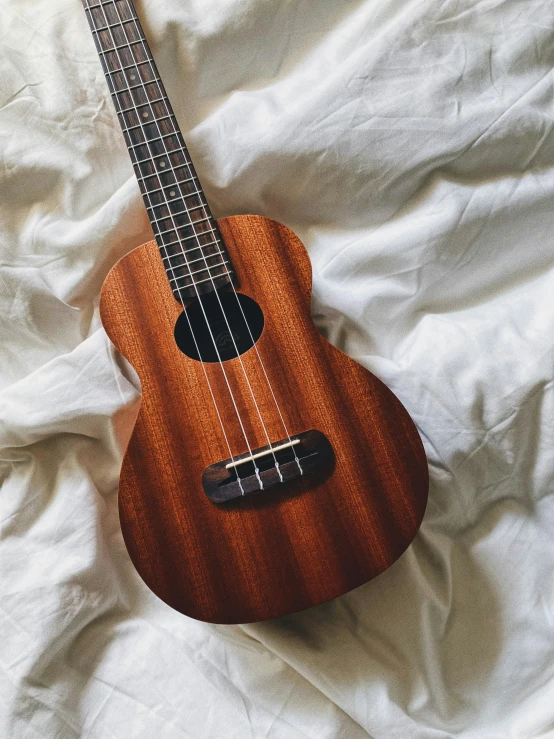 a ukulele laying on a white sheet