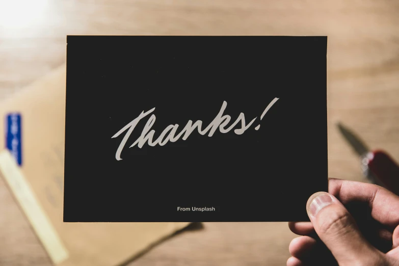 a person holding a card with the word thanks written on it