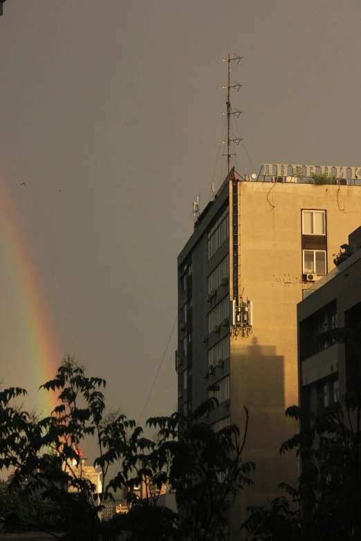 a tall building with a rainbow in the sky behind it