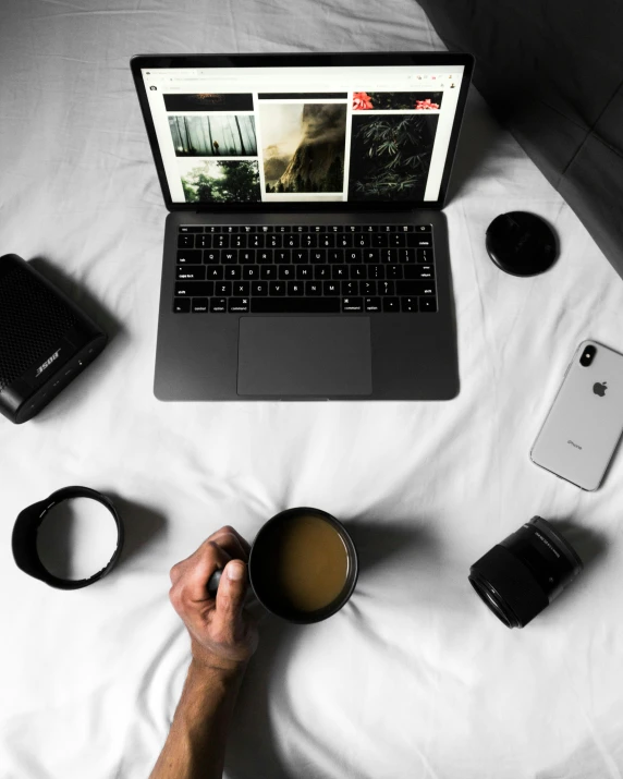 a person with their laptop sitting on a bed