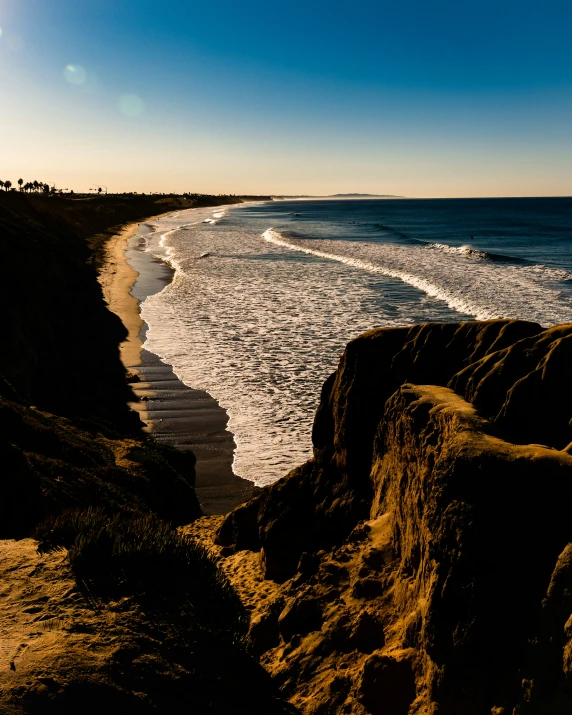 the sun shines brightly in the blue sky near a rocky beach