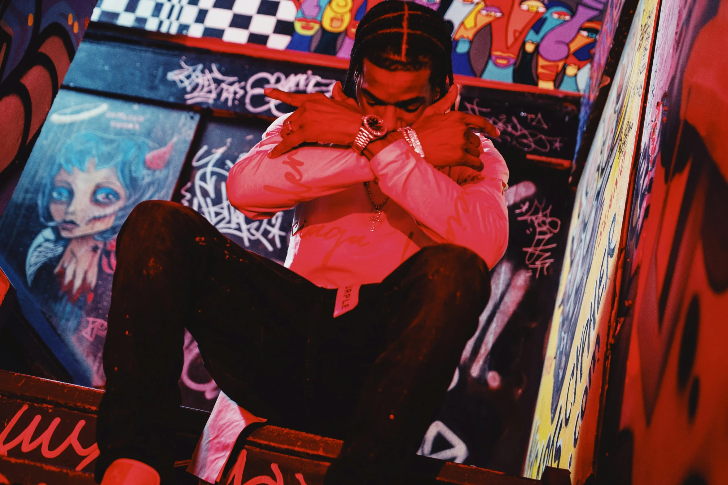 man in red jacket sitting on wall covered with graffiti