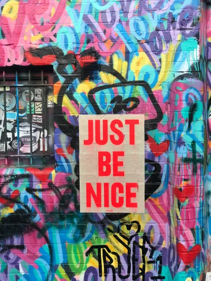 a piece of graffiti is placed next to a wall with the words just be nice