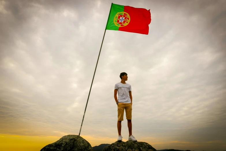man holding a red and green flag standing on top of a mountain