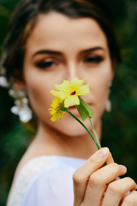 a woman in white holding a yellow flower