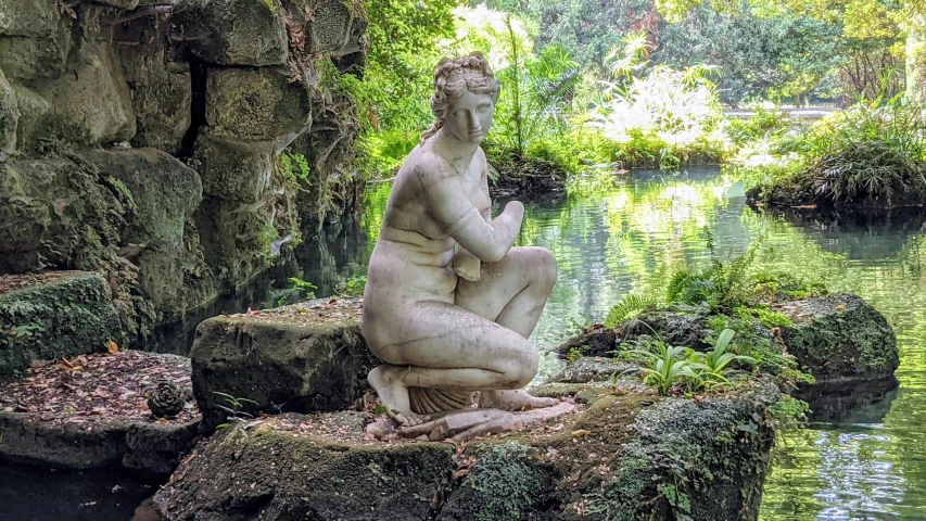 a statue sits on top of a rock in a small creek