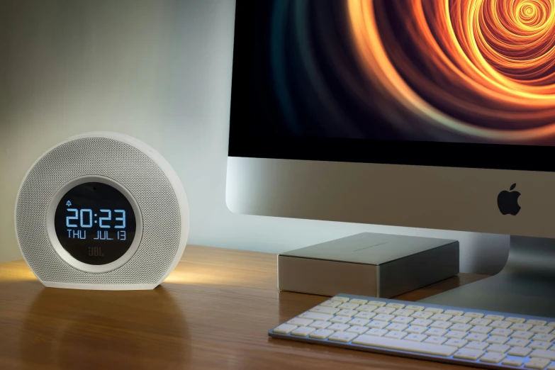 a clock is placed next to a keyboard and monitor