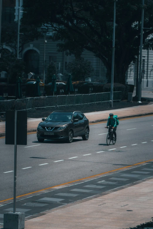 a person riding a bike near a car and street