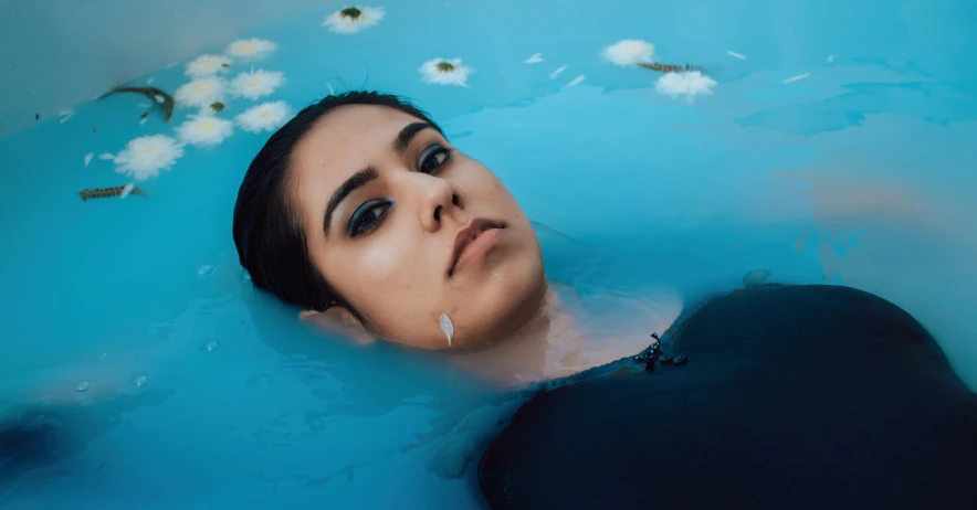 a woman with flowers and hair blowing in the water