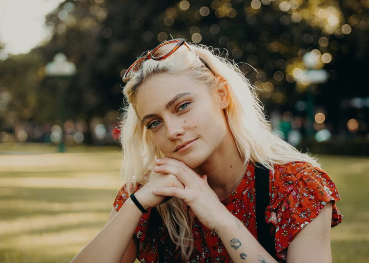 a woman sitting in the grass with her chin under her arm