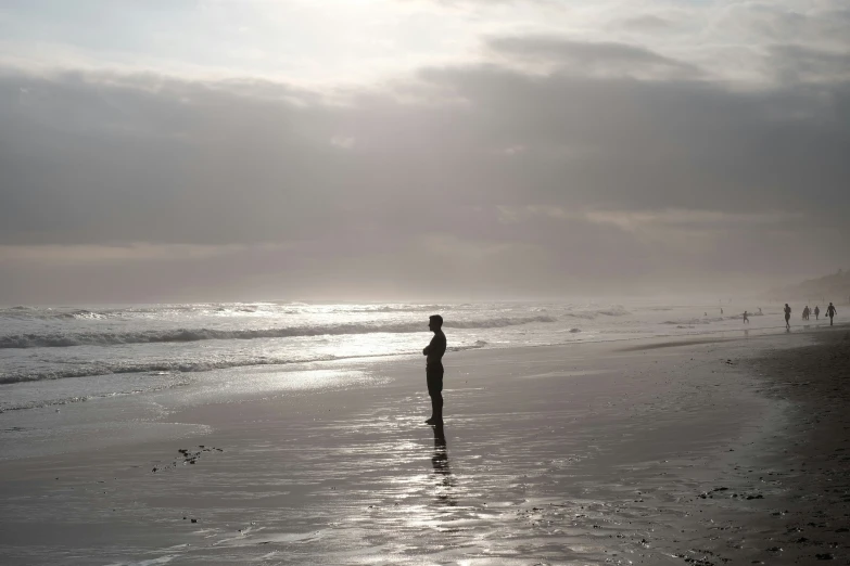 two people walking along the beach near some water