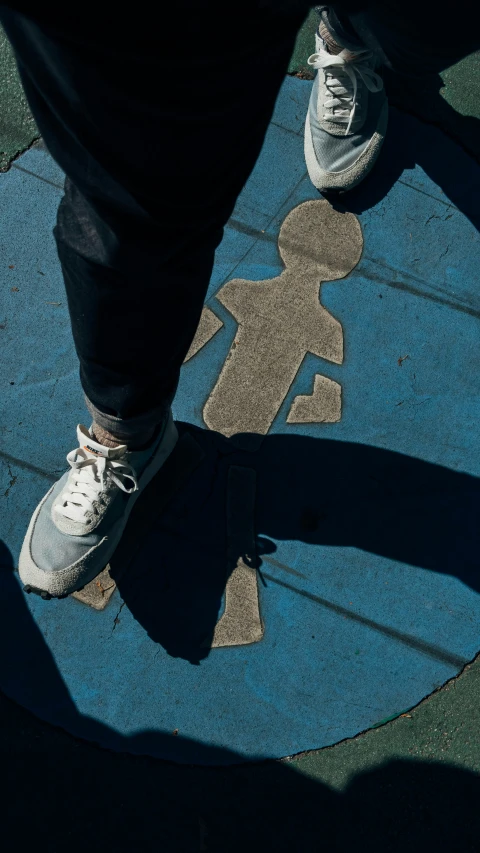 a persons shadow with his shoes on a circular blue area