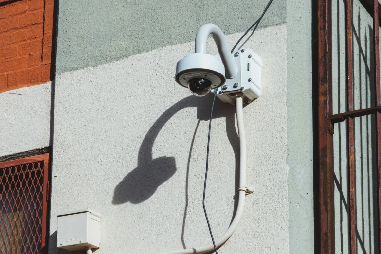 a white security camera mounted on the side of a building