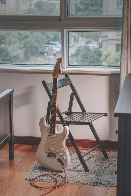 electric guitar sitting in front of a large window