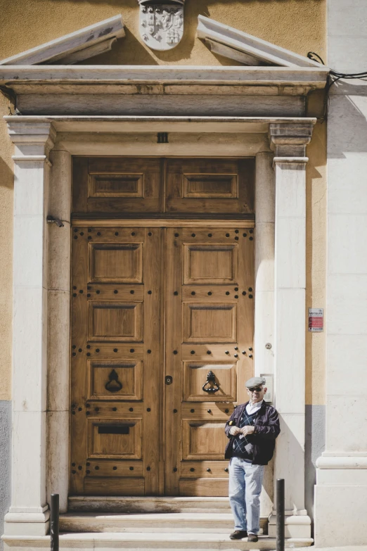 an elderly man leaning against the door of a building