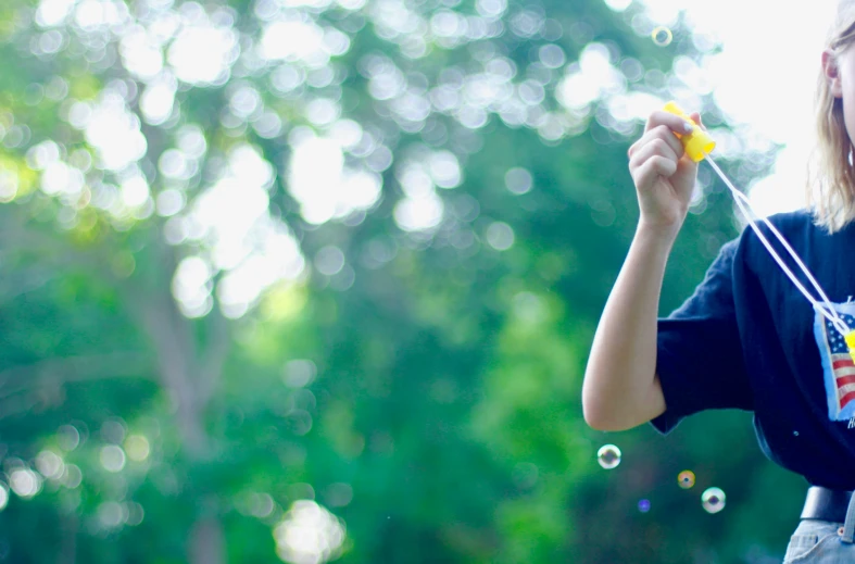 a small girl blowing soap bubbles off of a string