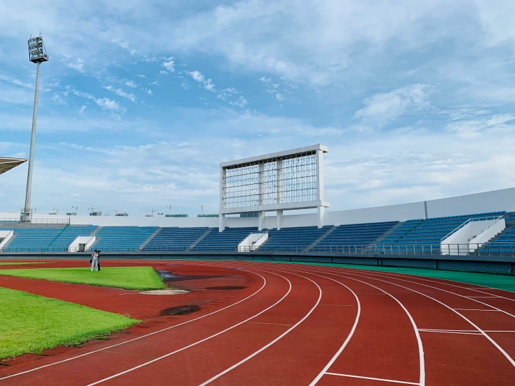 a red track and stadium with green grass