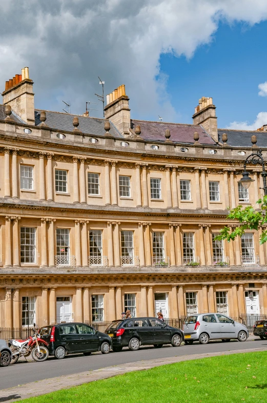 cars parked in front of a row of large stone buildings