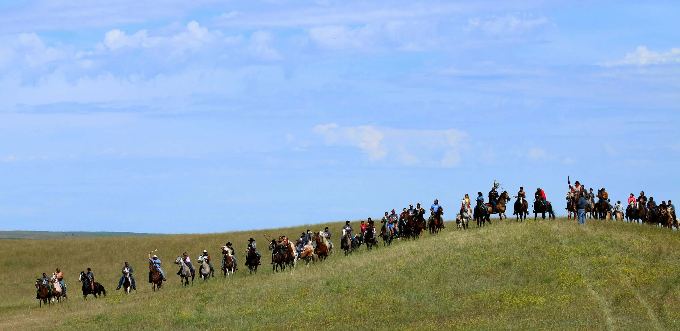 a group of people are riding horses down a hill