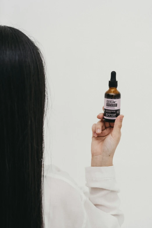 a woman is using an essential bottle to remove her hair