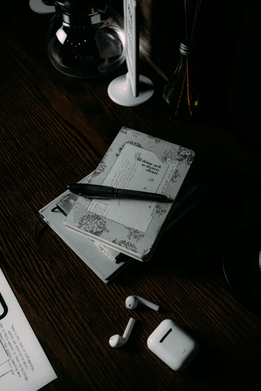 an open notebook, pen and headphones on a desk