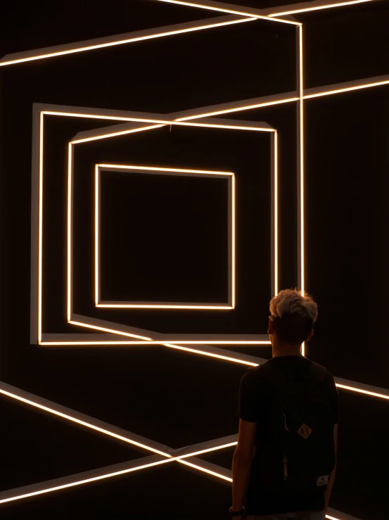 a man standing under neon lights looking down