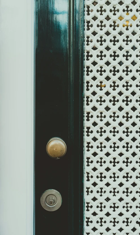 the doors are green and open next to a decorative wall