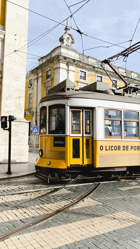 a yellow and white trolly car on a track with buildings in the background