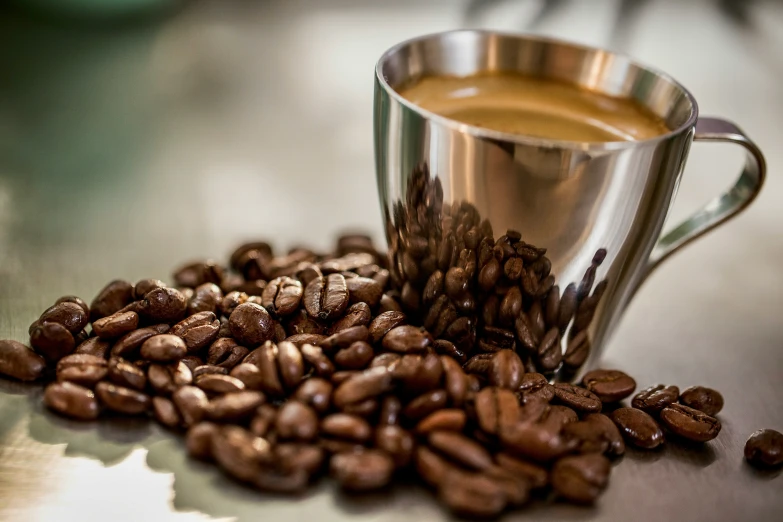 an open cup filled with coffee beans next to a spoon