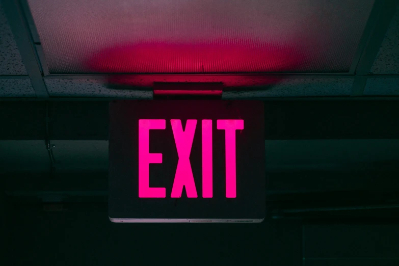 a pink exit sign with the light on in the dark