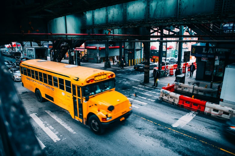 a yellow school bus driving past a parking lot