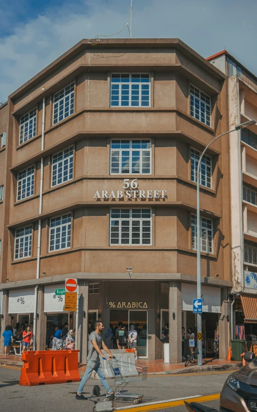 a man walks down a road in front of a large brown building