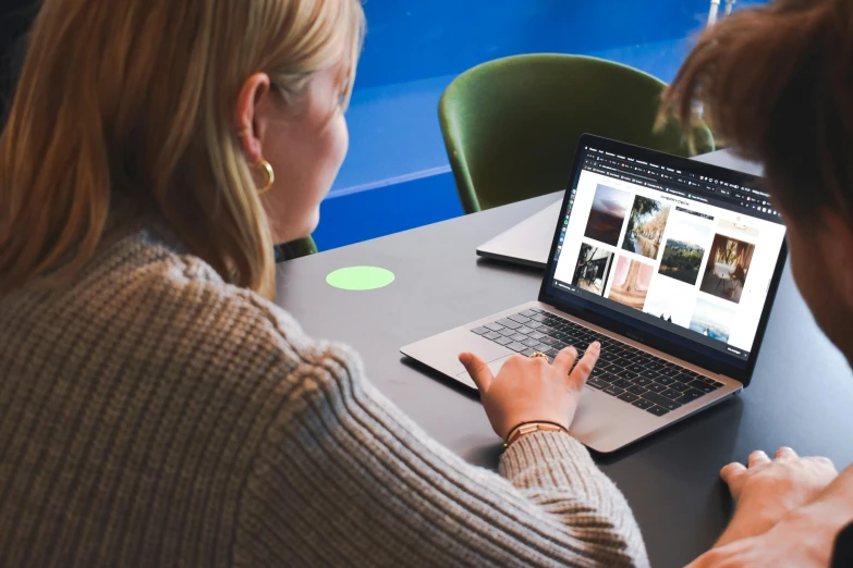 two women sitting at a table working on laptop computers