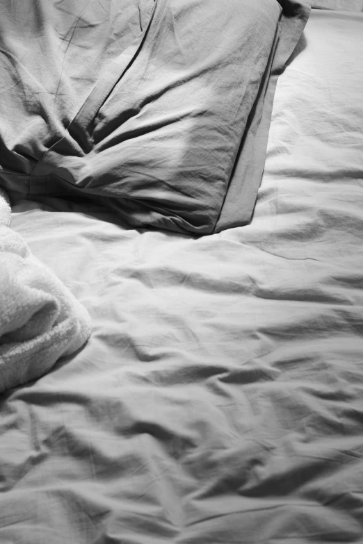 a bear laying on top of a bed covered in sheets